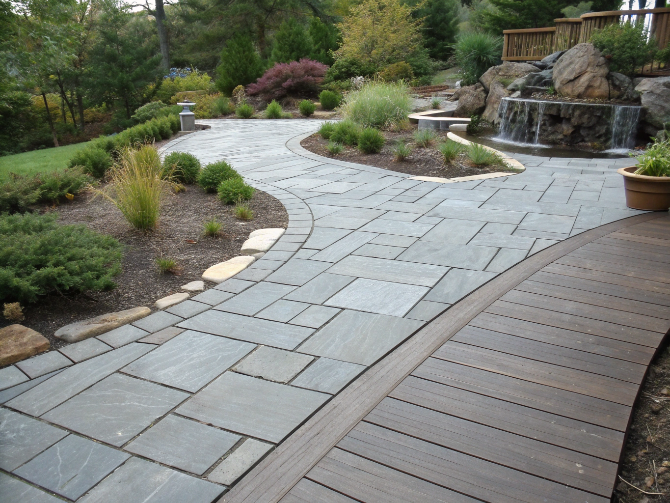 Hardscape design featuring natural stone patio and small waterfall